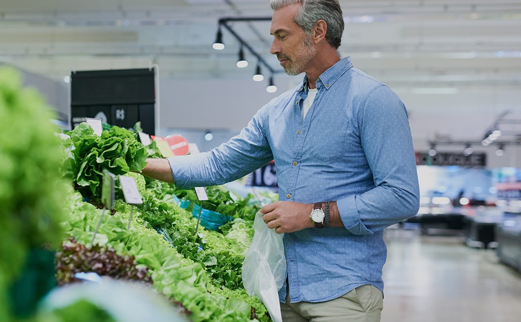 man shopping for cabbage in supermarket